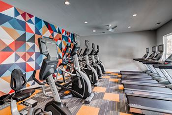 a row of cardio exercise machines in a gym
